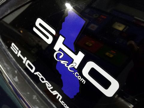 1993 Ford Taurus - A sticker with 'SHO Cal.com' and a blue outline of California is affixed to a dark surface, likely a car window.