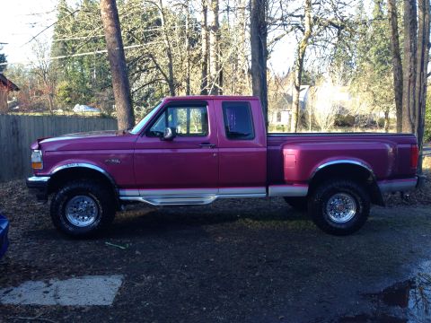 1992 Ford F-150 - This purple Ford F-150 pickup truck is parked outdoors on a gravel surface with trees in the background.