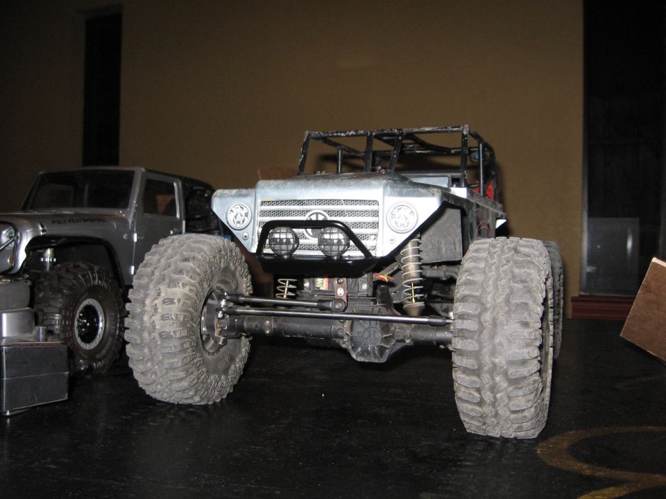 Front view of a remote control rock crawler truck with large tires, another SUV-like RC vehicle to the left