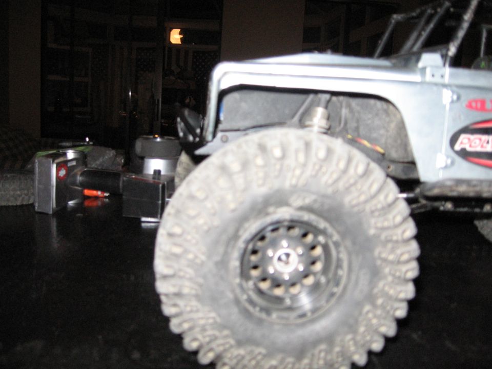Silver remote control car with large knobby tires and visible suspension components