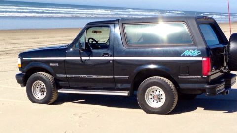 1992 Ford Bronco - Side view of a black 1992 Ford Bronco Nite edition on the beach.