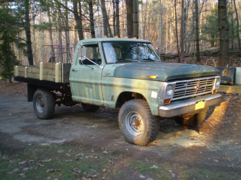 1979 Ford Bronco - This flatbed truck, likely a 1969 model based on its grille, is parked outdoors in a wooded area.