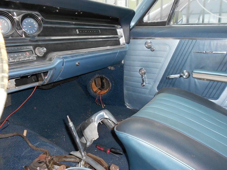 Blue interior of a classic car with dash gauges, bench seat and shifter removed