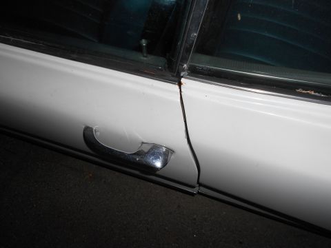 1965 Pontiac Catalina - A detail shot focuses on the door handle and trim of a white vehicle.