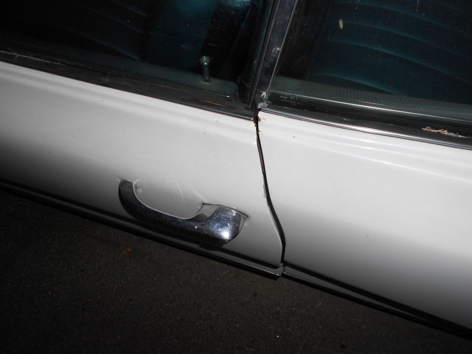Close-up of a white car's side door, showing the chrome door handle and window trim