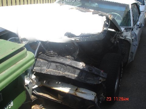 1965 Pontiac Catalina - The front of a heavily damaged 1965 Pontiac Catalina is visible, with its engine compartment exposed.