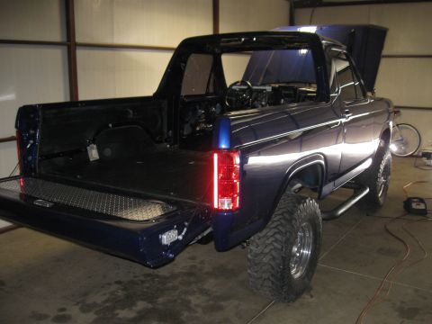 1982 Ford Bronco - This Ford Bronco is in a garage with its tailgate and hood open, showing its interior and engine bay.