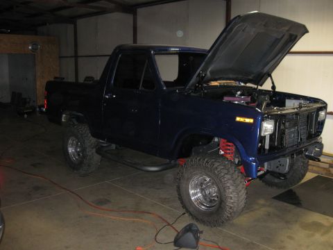 1982 Ford Bronco - This dark blue pickup truck has a lifted suspension and large off-road tires.