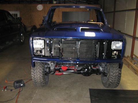 1982 Ford Bronco - Blue pickup truck in garage, front end disassembled, with another vehicle nearby.