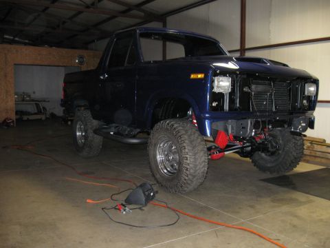 1982 Ford Bronco - This modified Ford Bronco is undergoing some work in a garage, with tools and wires visible on the floor.