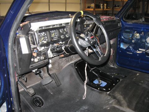 1982 Ford Bronco - Interior view of a blue vehicle, showing the dashboard, steering wheel, and pedals, with some panels removed.