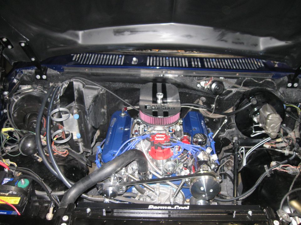 Engine bay with blue valve covers and a chrome air filter. Wires and hoses are visible