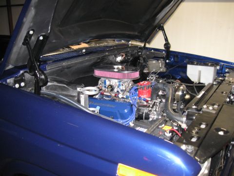 1982 Ford Bronco - Engine bay of a 1982 Ford Bronco, a blue engine with chrome accents and an open hood.