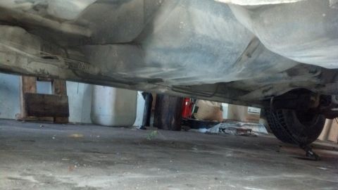1985 Mercury Grand Marquis - The underside of a 1985 Mercury Grand Marquis is visible, including the exhaust system and a rear tire.