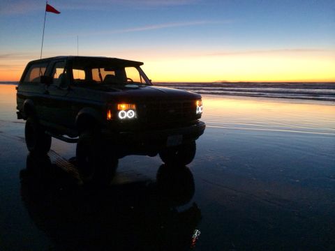 1992 Ford Bronco - Ford Bronco parked on a beach during a colorful sunset.