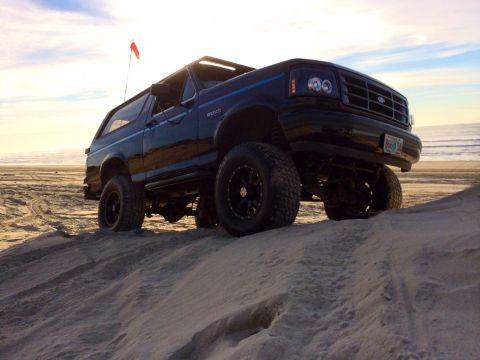 1992 Ford Bronco - This lifted Ford Bronco is shown on a sandy beach with the ocean in the background.