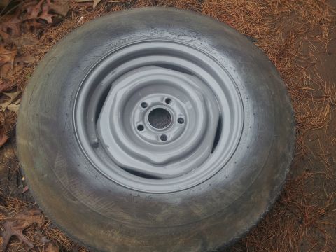 1986 Ford Bronco - A single tire and rim assembly rests on the ground, surrounded by pine needles and fallen leaves.