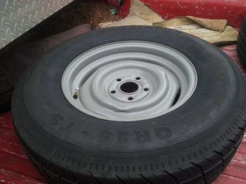 1986 Ford Bronco - Spare tire and wheel assembly resting in the bed of a red truck.