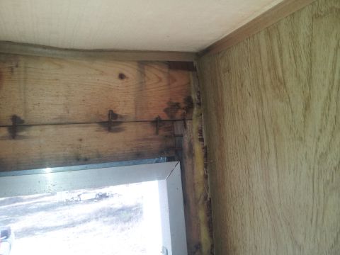1986 Ford Bronco - The interior of a vehicle shows signs of water damage on the wood paneling and around the window frame.