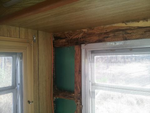 1986 Ford Bronco - Damage to the interior wall structure, revealing exposed wood and insulation near a window.