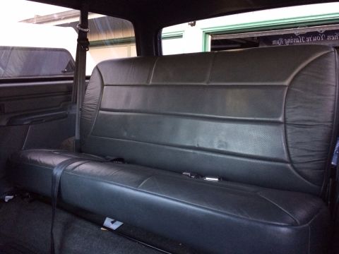 1992 Ford Bronco - Rear interior view of a vehicle's black leather seat and seatbelt.