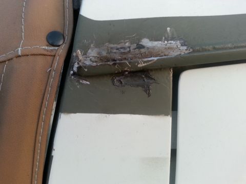 1992 Ford Bronco - Close-up of rust and repair on a vehicle's body panel, with a canvas cover visible.