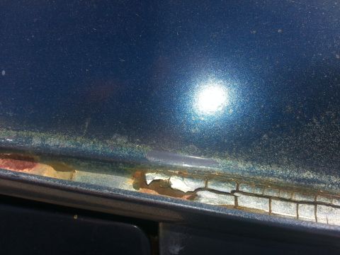 1994 Ford Bronco - Close-up view of rust damage on the rain gutter of a blue vehicle.