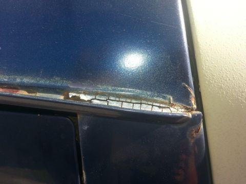 1994 Ford Bronco - Peeling paint and rust are visible on the door frame of this blue vehicle.