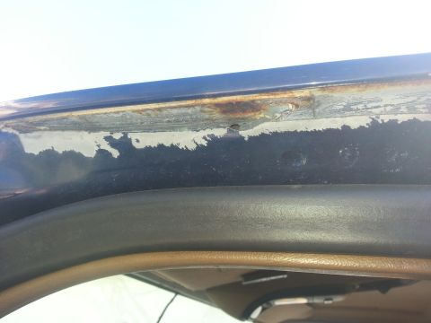 1994 Ford Bronco - Close-up of rust damage on a vehicle's rain gutter, indicating wear and tear.