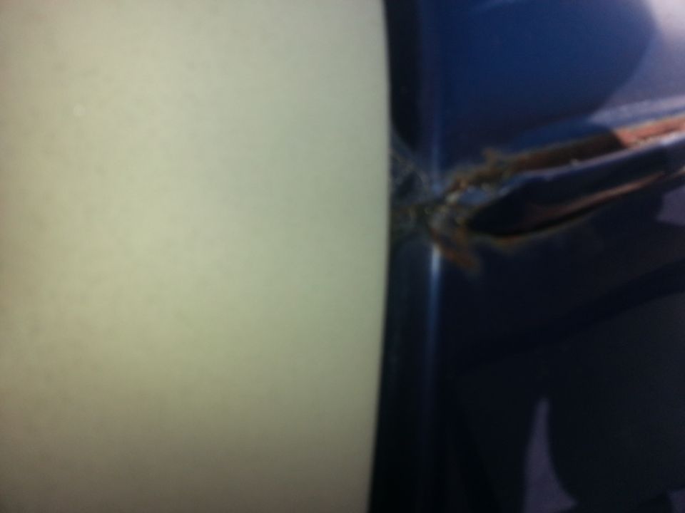 Close-up of rust forming at the seam of a blue car door