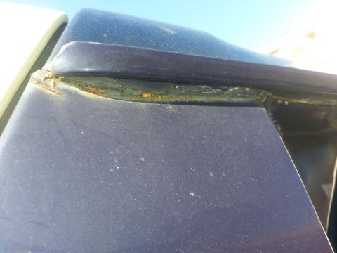 1994 Ford Bronco - Rust is visible around the window seal on the roofline of a dark blue vehicle.