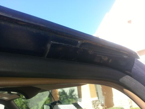 1994 Ford Bronco - Close-up of a dark blue vehicle's rain gutter showing signs of rust and wear.