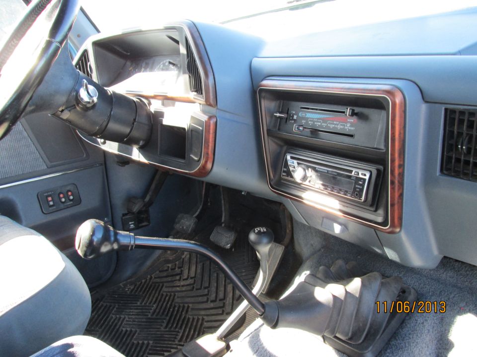 Truck interior with blue dashboard, aftermarket stereo, and floor shifter
