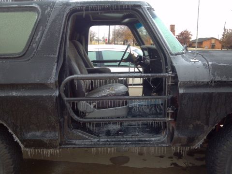 1978 Ford Bronco - A black 1978 Ford Bronco is seen from the side with its door open, heavily coated in ice.