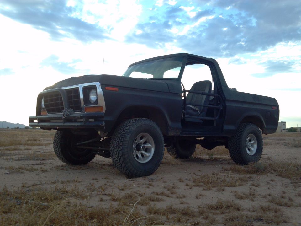 Black 1978 Ford Bronco parked on dirt with sky in background