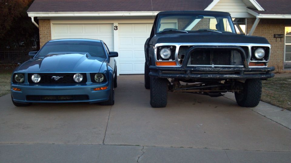 Front view of a black pickup truck with a brush guard and a blue Mustang