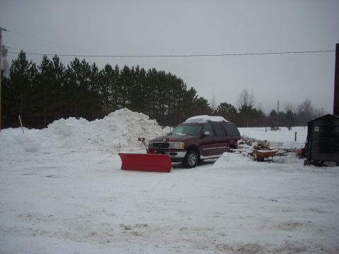 1963 Hummer H3 - Maroon SUV equipped with a snow plow sits in a snowy landscape, suggesting a winter scene.