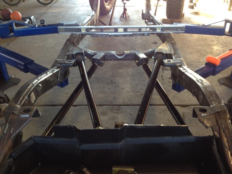 Vehicle frame assembly on jack stands with a level across the top