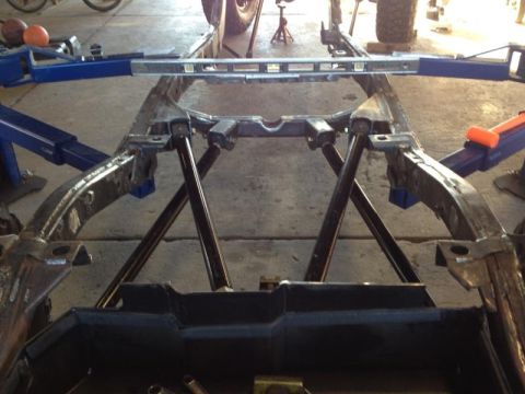 1985 Jeep CJ7 - The frame of a vehicle is supported by jack stands and a lift, with a level placed across it.