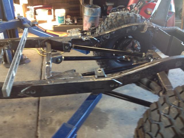 Jeep CJ frame on a lift, with suspension components and a tire visible