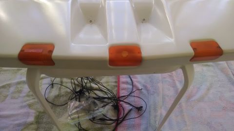 1995 Ford Bronco - A white plastic automotive part with four amber marker lights and associated wiring is shown, resting on a patterned cloth.