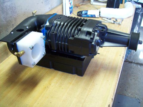 2001 Ford Ranger - A black supercharger unit with a white adapter and brass fittings is displayed on a wooden surface.