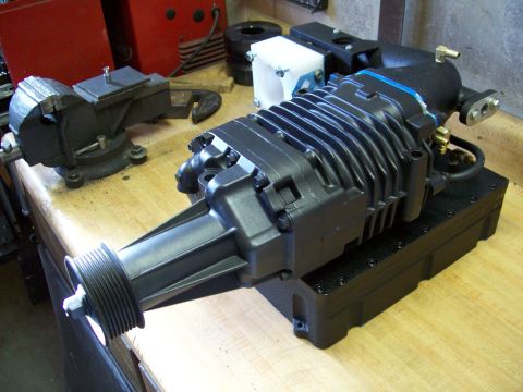 2001 Ford Ranger - A supercharger assembly sits on a wooden workbench next to a vise and other shop equipment.