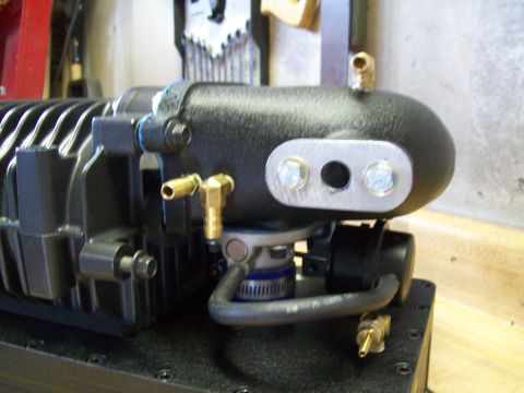 2001 Ford Ranger - A close-up view of a black supercharger with various brass fittings and a metal plate attached.