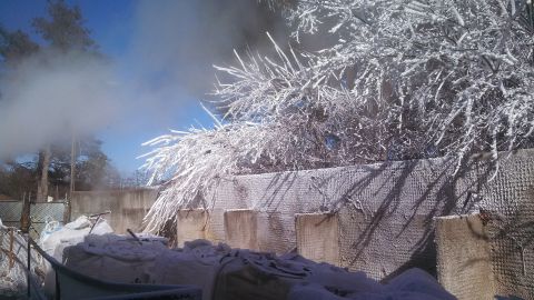 1979 Ford Bronco - A winter scene unfolds with snow-laden branches and a mysterious plume of smoke rising into the clear blue sky.