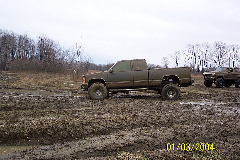 Muddy lifted pickup truck and SUV in a muddy field