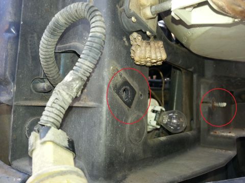 1994 Ford Bronco - A close-up view of a vehicle's headlight assembly shows a wasp nest and exposed wiring.