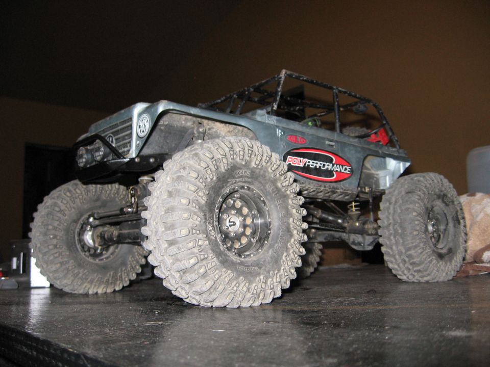 RC rock crawler toy with large knobby tires and roll cage, "POLYPERFORMANCE" decal on side