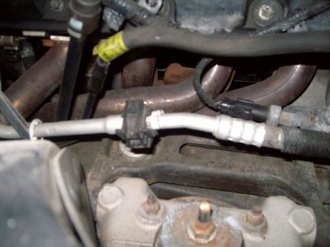 2004 Ford Crown Victoria - Detail shot of engine parts, likely from a vehicle's exhaust and air conditioning system.