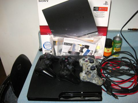 1992 Ford Mustang - A PlayStation 3 console is shown with three controllers, cables, and various accessories, including cans of oil and cleaner.